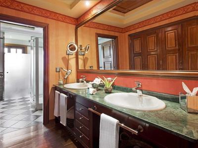 Prostorná koupelna s dvojitým umyvadlem, zrcadlem a přístupem k sprše.