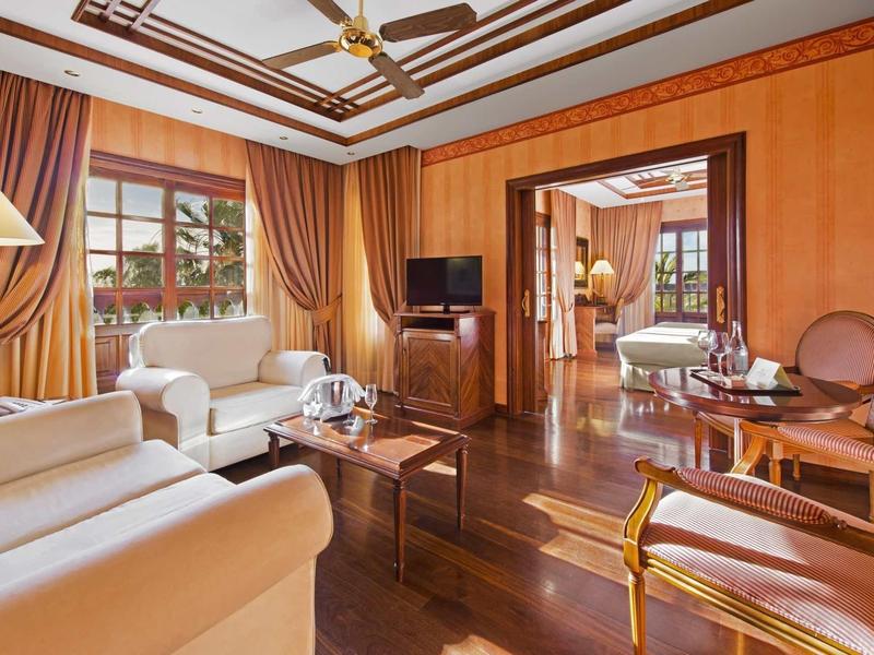 Elegantní obývací pokoj s posezením, velkým oknem a dřevěnými podlahami v hotelovém pokoji.