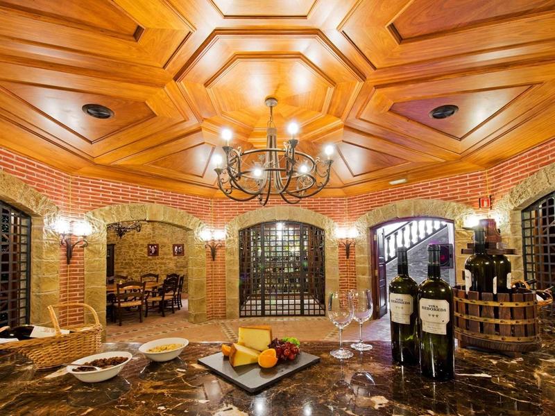 Luxusní vinný sklep s dřevěným stropem, mramorovou deskou a lahvemi vína ve stylové místnosti.