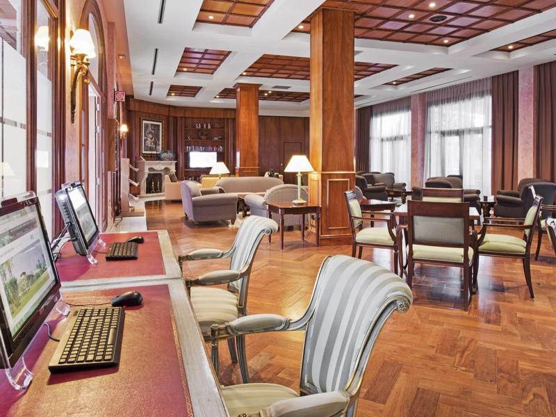 Elegantní hotelová lounge s počítači a sezením na dřevěné podlaze.