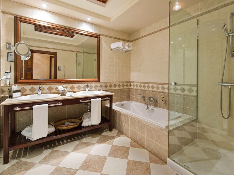 Moderní koupelna s velkou vanou, sprchou a dvojumyvadlem pod velkým zrcadlem.