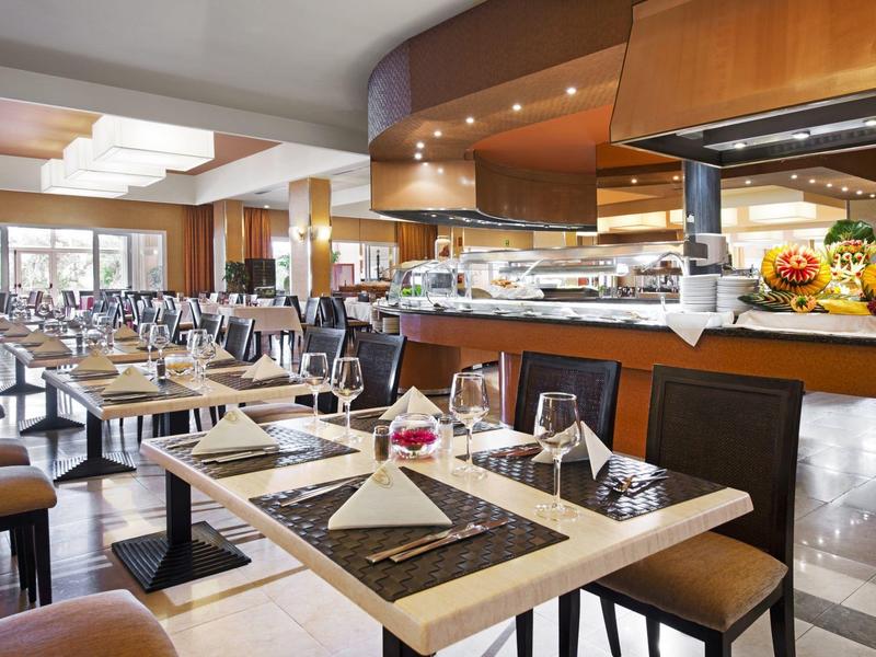 Restaurante moderno de hotel con mesas preparadas y área de buffet en ambiente luminoso.