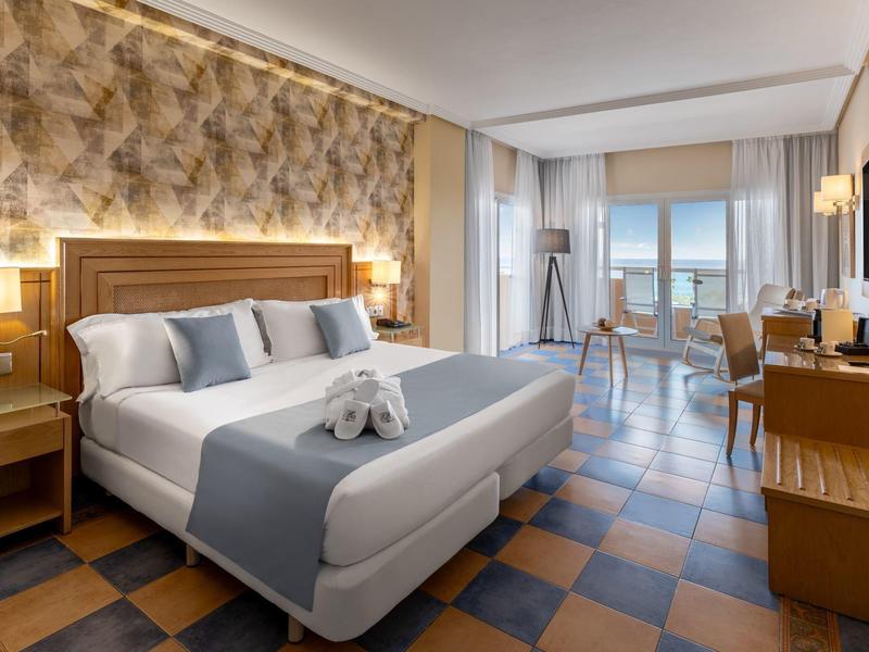 Habitación de hotel moderna con cama doble, decoración elegante y vistas al mar desde el balcón.
