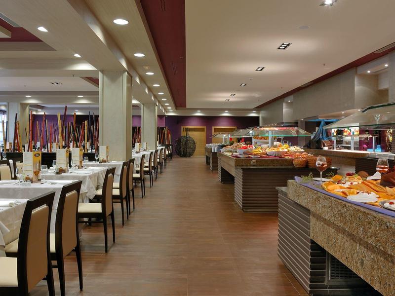 Elegante eetzaal in hotel met buffet en gedekte tafels in warm licht.