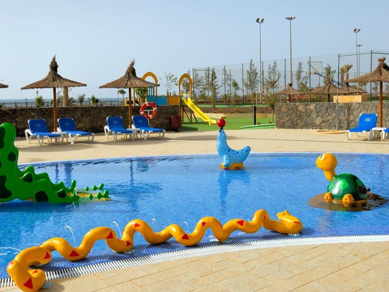 Kinderzwembad met kleurrijk waterspeelgoed en ligstoelen op de achtergrond