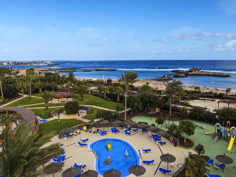 Uitzicht op zwembad en tuin met zee op de achtergrond op een zonnige dag