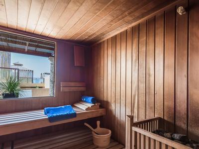 Holzsauna mit Holzwänden, Fenster, Holzbänken, blauem Handtuch und Holzgefäß.