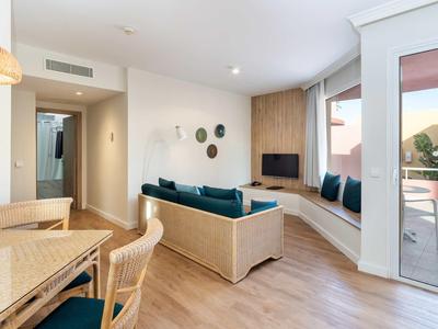 Helles Wohnzimmer mit Holzboden, großer Fensterbank, hellen Möbeln und Zugang zur Terrasse.