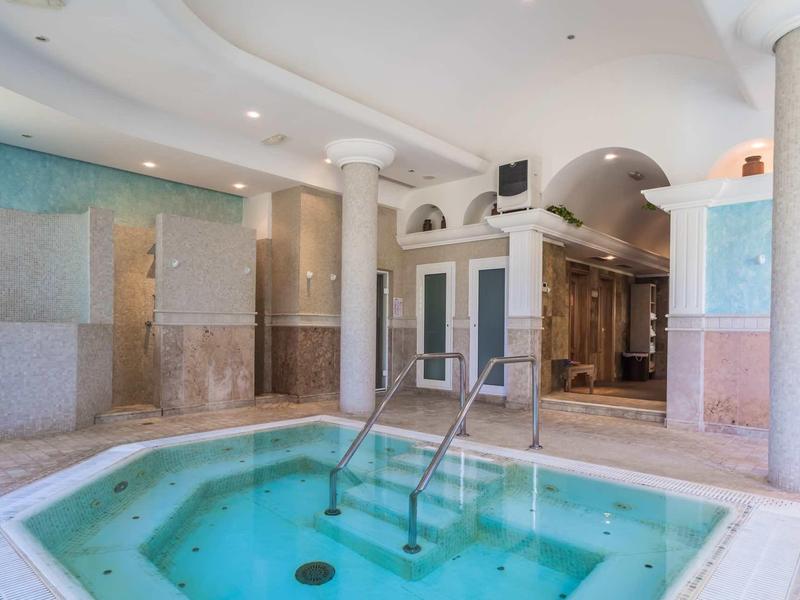 Area interna di un hotel con vasca idromassaggio quadrata e colonne in marmo.