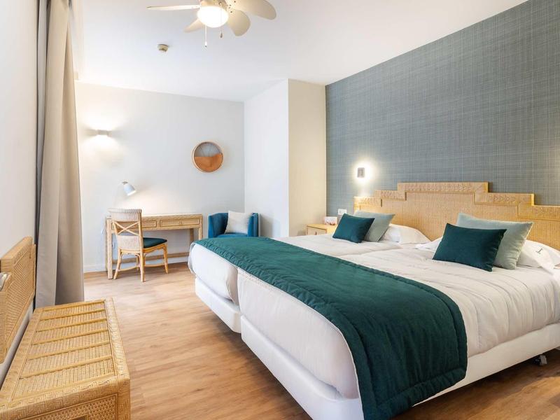 Camera d'hotel moderna con letto matrimoniale e scrivania in tonalità calde.