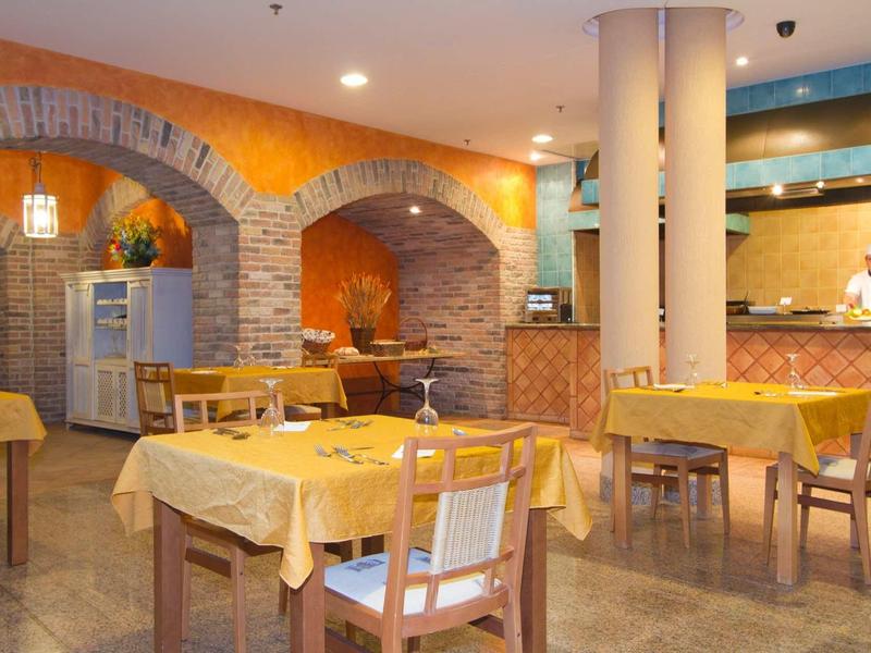 Accogliente sala ristorante dell'hotel con tovaglie gialle e pareti ad arco in mattoni.