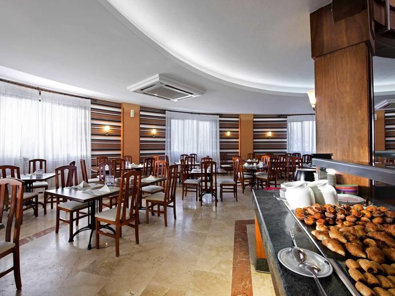 Moderner Frühstücksraum mit Holzmöbeln, gedeckten Tischen und einem Buffet mit Gebäck.