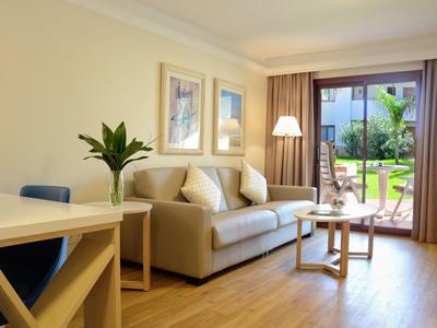 Helles Wohnzimmer mit grauem Sofa, Holzfußboden, Couchtisch und großem Fenster zum Garten.