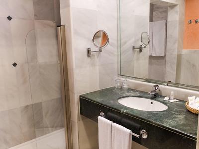 Modernes Badezimmer mit Glasdusche, großem Spiegel und dunkelgrünem Waschbecken aus Marmor.