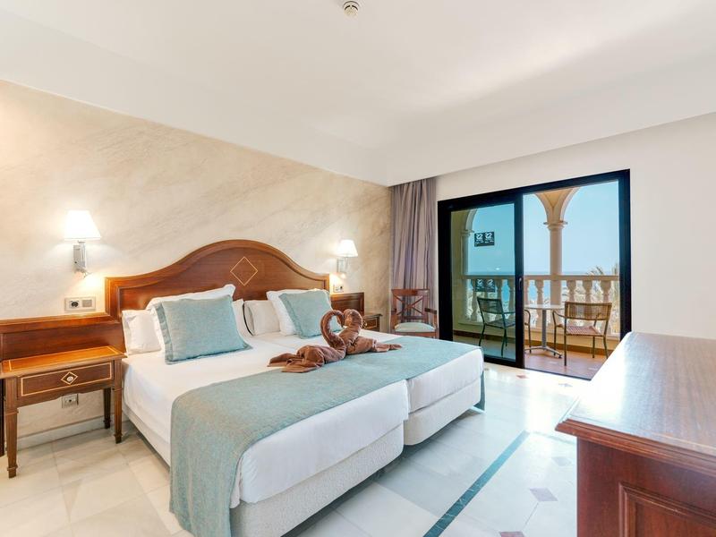 Chambre d'hôtel lumineuse avec lit double, balcon et vue sur la mer