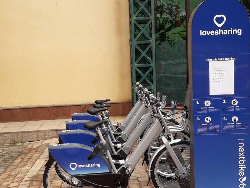 Vélos de location garés à côté d'un bâtiment jaune sur un sol pavé.