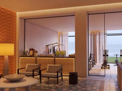 Moderne hotel lounge met warme verlichting, twee stoelen, een tafel en uitzicht op het terras en de zee.