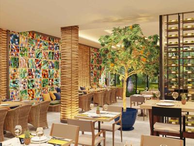 Modern hotelrestaurant met kleurrijke muur, bakstenen zuilen, groene planten en elegante eettafels.