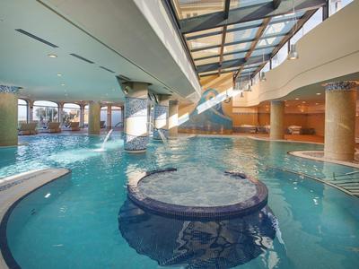 Binnenzwembad met jacuzzi, waterpartijen en glazen dak voor zonlicht