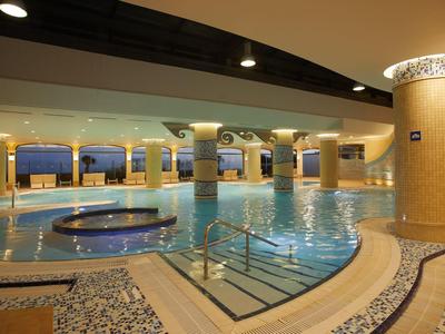 Overdekt zwembad met jacuzzi en sfeerverlichting in een ruime hotel spa