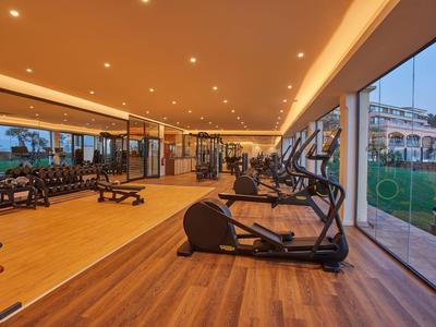 Palestra moderna con attrezzature cardio e ampie finestre che si affacciano su un giardino.