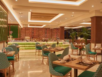 Ristorante dell'hotel moderno con sedie verdi e tavoli elegantemente apparecchiati.