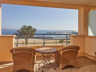 Gezellig balkon met stoelen en tafel met uitzicht op palmboom en strand