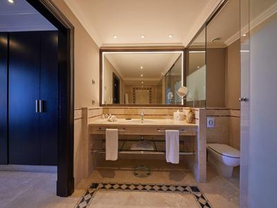 Moderne hotelbadkamer met dubbele wastafels, grote spiegel en handdoeken onder het aanrecht.