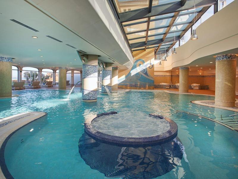 Binnenzwembad met jacuzzi, waterpartijen en glazen dak voor zonlicht