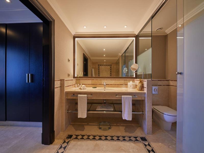 Moderne hotelbadkamer met dubbele wastafels, grote spiegel en handdoeken onder het aanrecht.