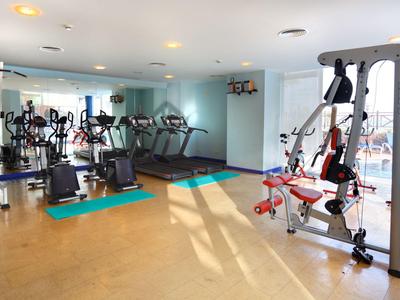 Modern gym with various exercise machines and large mirrors.