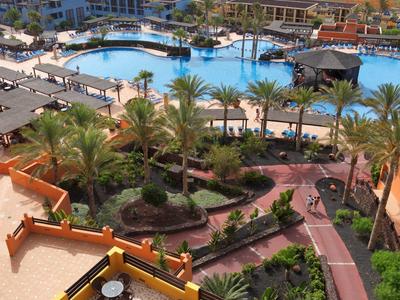 Basen z tarasami, palmami i widokiem na plażę oraz morze na horyzoncie.