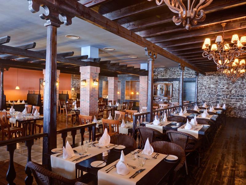 Elegancka sala restauracyjna z nakrytymi stołami i widocznymi drewnianymi belkami.