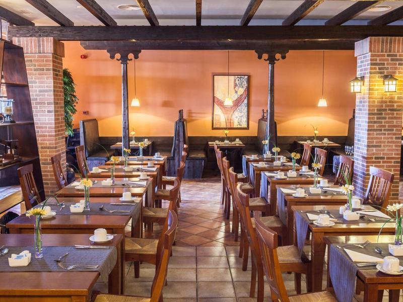 Przytulna sala restauracyjna z drewnianymi stołami i ciepłym oświetleniem.