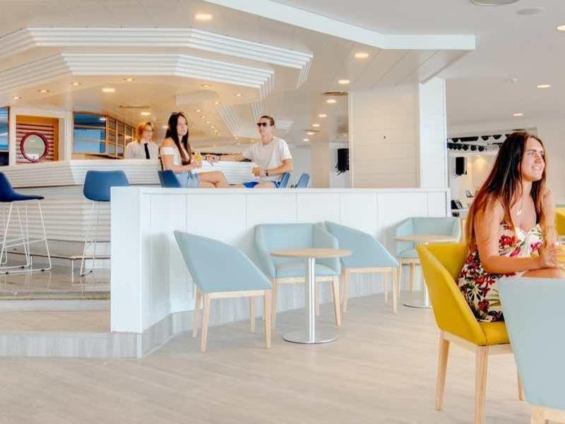 Interno di un ristorante di un hotel moderno con mobili chiari e ospiti che pranzano.