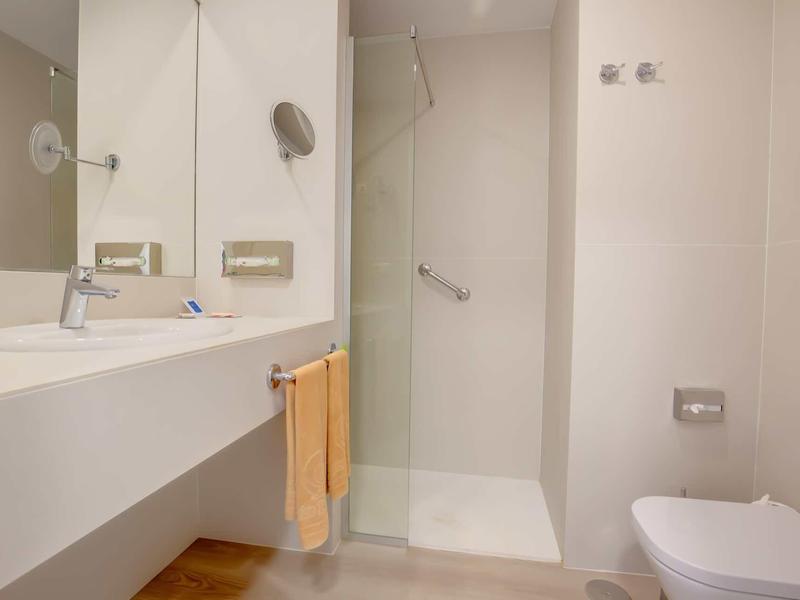 Bagno luminoso e moderno con doccia, lavabo, specchio e toilette.