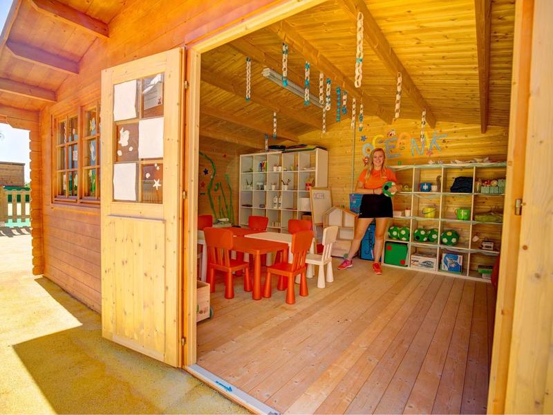 Interno di una casa in legno con scaffali e tavoli e sedie per bambini.