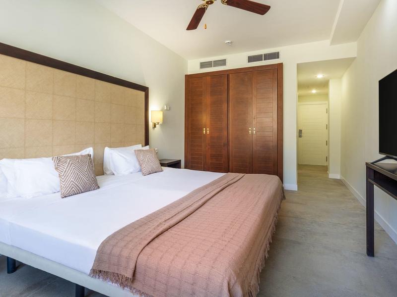 Nowoczesny pokój hotelowy z dużym łóżkiem, drewnianą szafą i telewizorem.