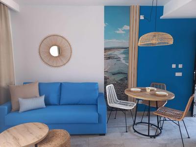 Salon moderne avec canapé bleu, table à manger et décoration murale maritime.