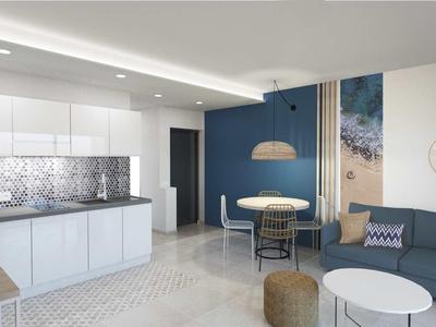 Salon moderne avec canapé bleu, tables rondes et cuisine ouverte.