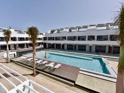 Piscina moderna dell'hotel con lettini e palme sotto un cielo sereno