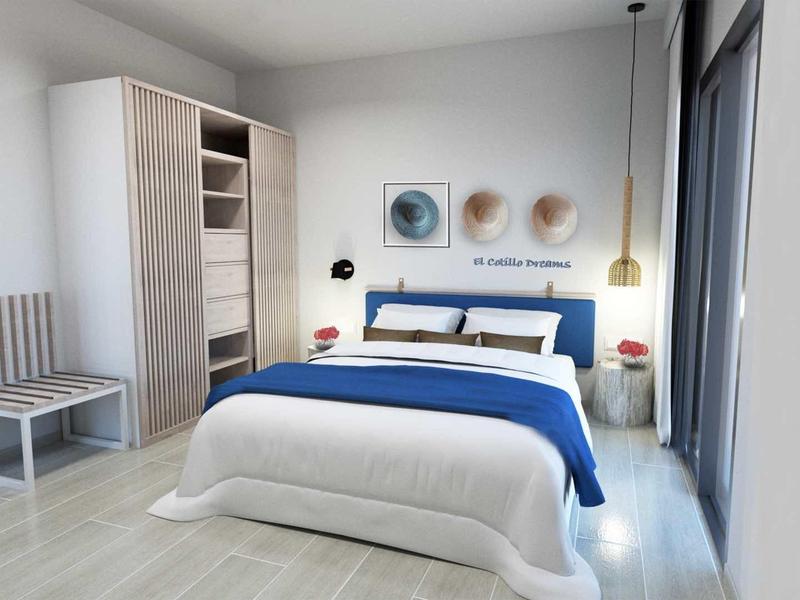 Chambre lumineuse et moderne avec grand lit, literie bleue et blanche, et décoration minimaliste.
