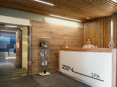 Recepción de spa con paredes de madera, mostrador iluminado y personal en el mostrador.