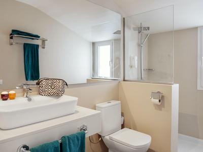 Hell gestaltetes Badezimmer mit Waschbecken, WC und Duschbereich in neutralen Farben.