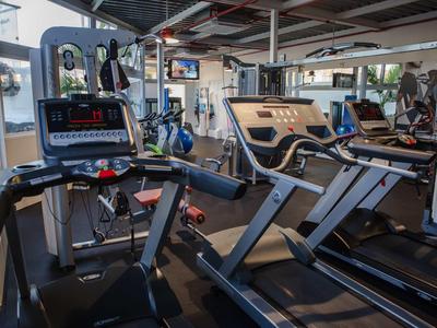 Gimnasio moderno con cintas de correr, máquinas de entrenamiento y grandes ventanas con vistas.