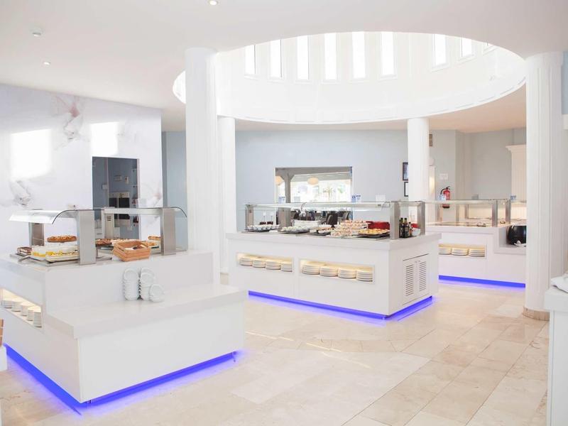 Bright, modern buffet area with white furniture and blue LED lighting in a hotel.