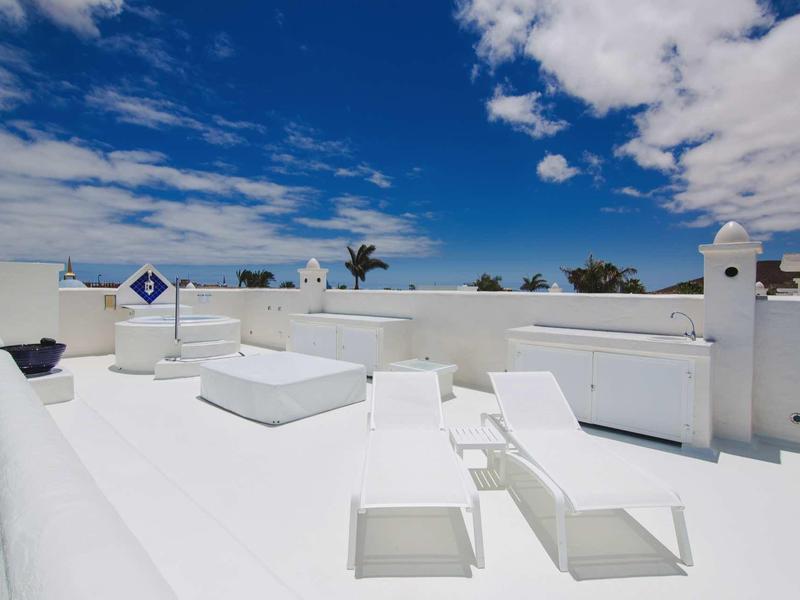 White sun terrace with loungers under a blue sky with clouds
