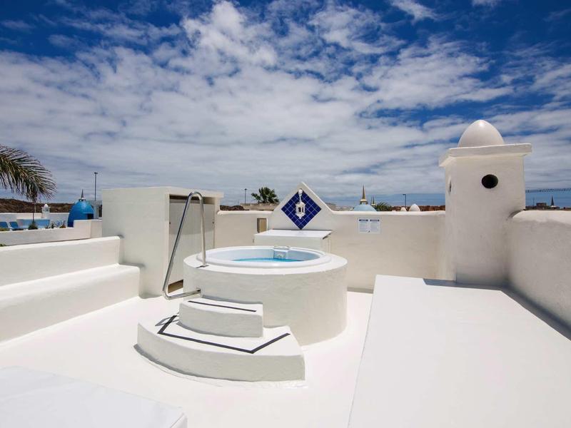 White rooftop with hot tub and blue sky under sunny weather.