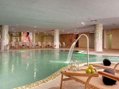 Indoor pool area with water jets, lounge chairs, and a relaxed ambiance in warm lighting.