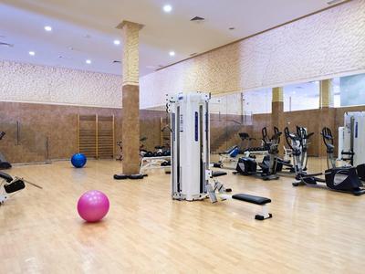 Spacious gym with exercise machines, stability balls, and mirrors on the wall.